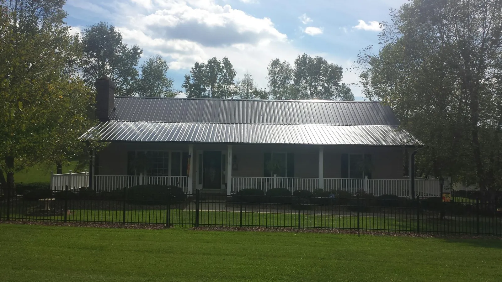 Gray metal roof on a brick ranch with a full width front porch — Gutter Guard Installation work by our crew in Buena Vista